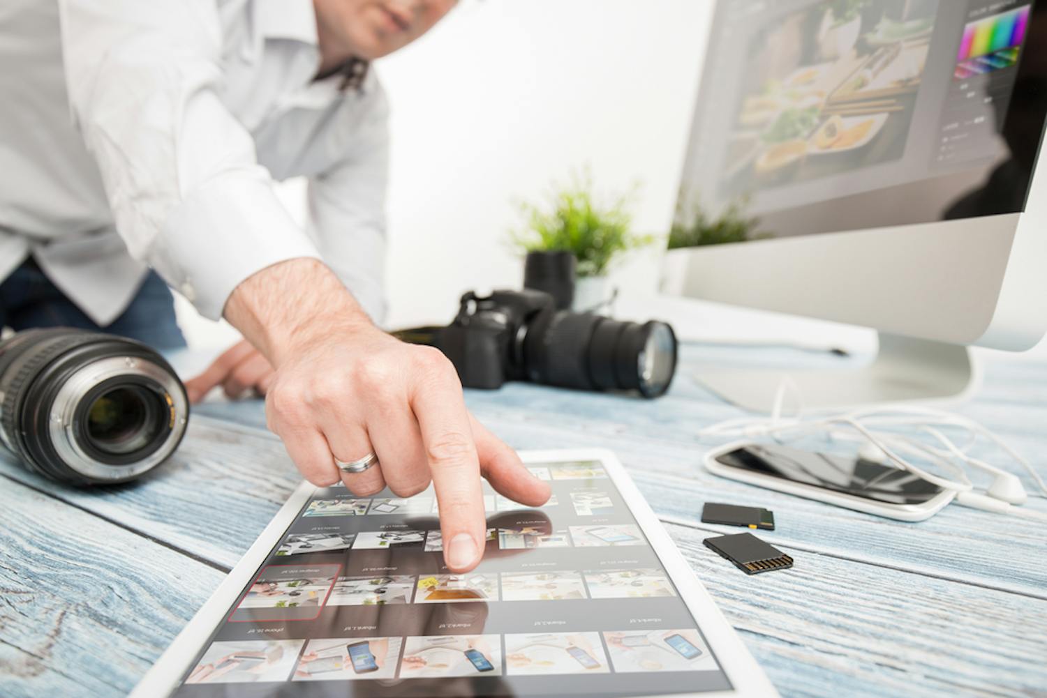 fotograf raekker ud efter tablet som bruges til billedbehanling Man pekar på surfplatta där han har ett bildbehandlingsprogram öppet